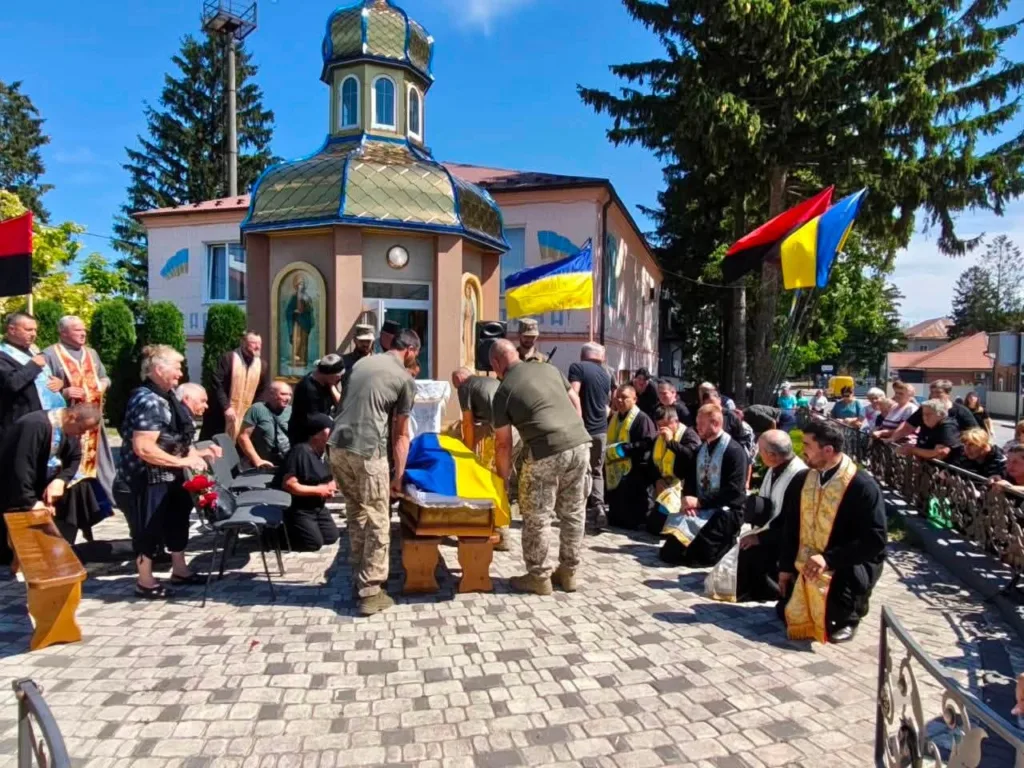 Прощання з військовим біля храму під українськими прапорами
