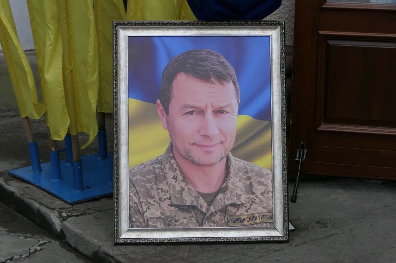 Портрет українського військового біля державних прапорів