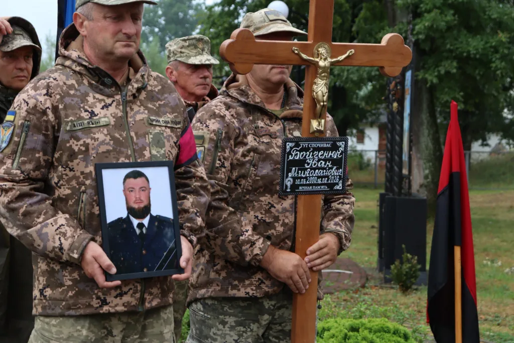 Військові на похороні тримають портрет і хрест полеглого