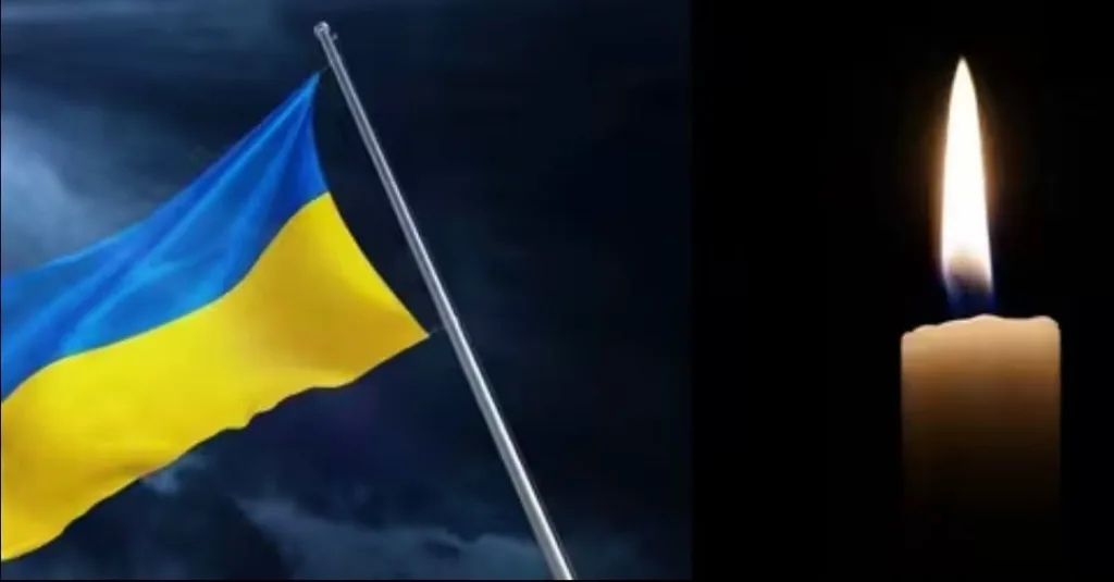 Український прапор і запалена свічка на темному тлі