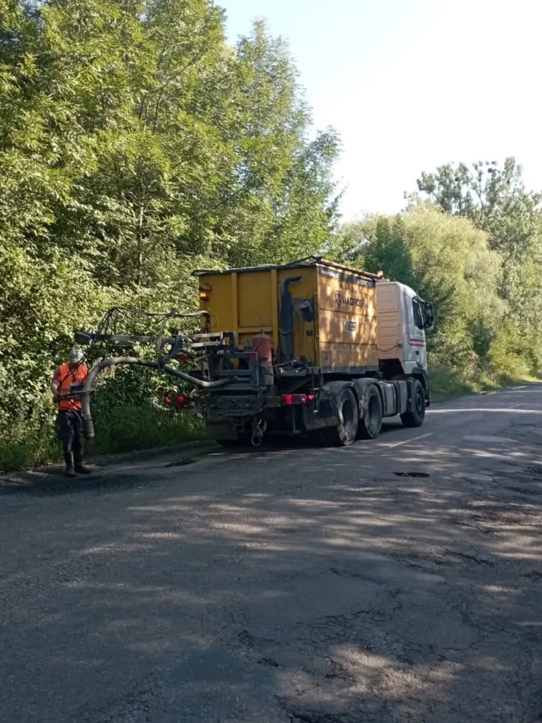 Дорожня машина ремонтує узбіччя біля лісу