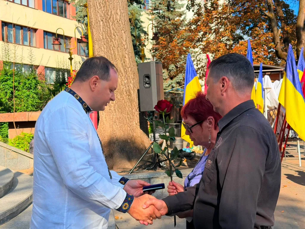 Вручення відзнаки родині на тлі українських прапорів