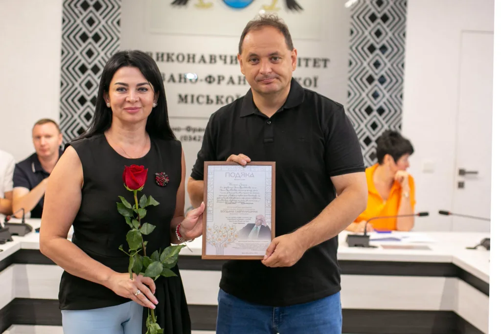 Чоловік вручає жінці подяку та троянду