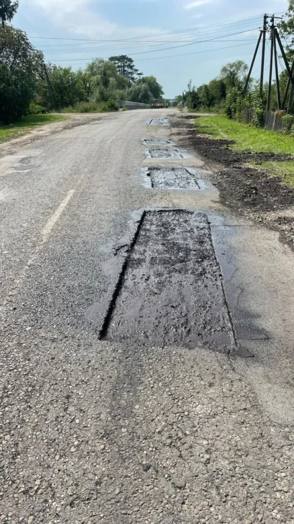 Сільська дорога з ділянками свіжого ямкового ремонту