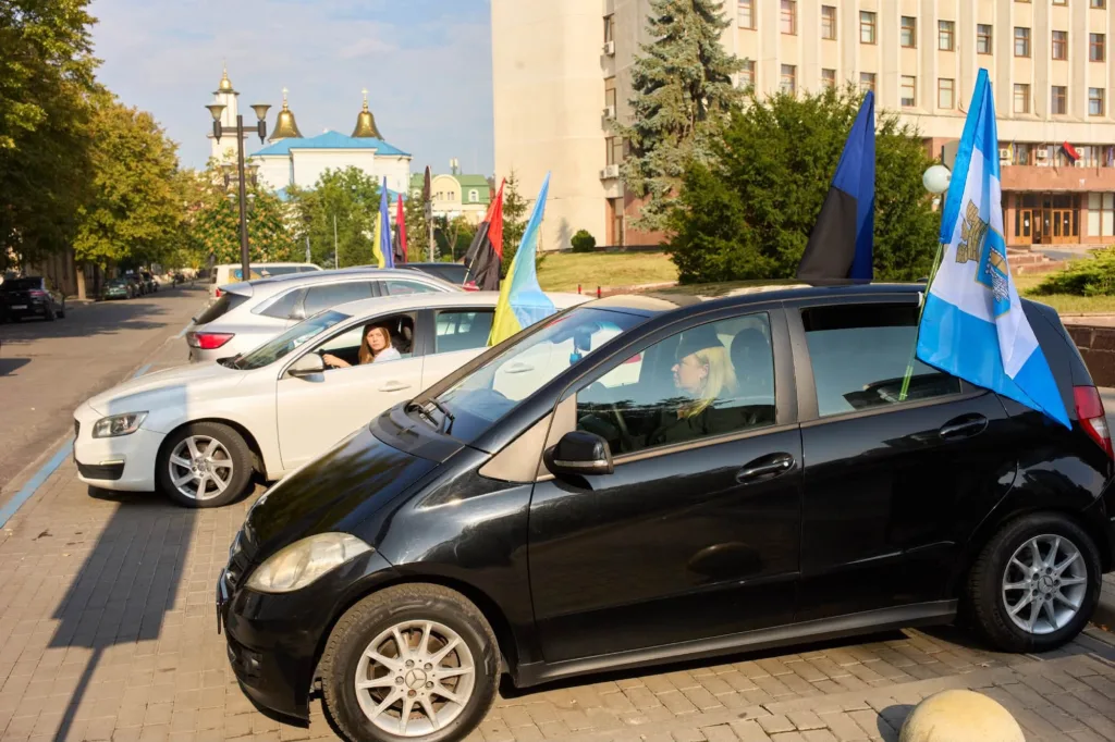 Автомобілі з прапорами біля міської будівлі