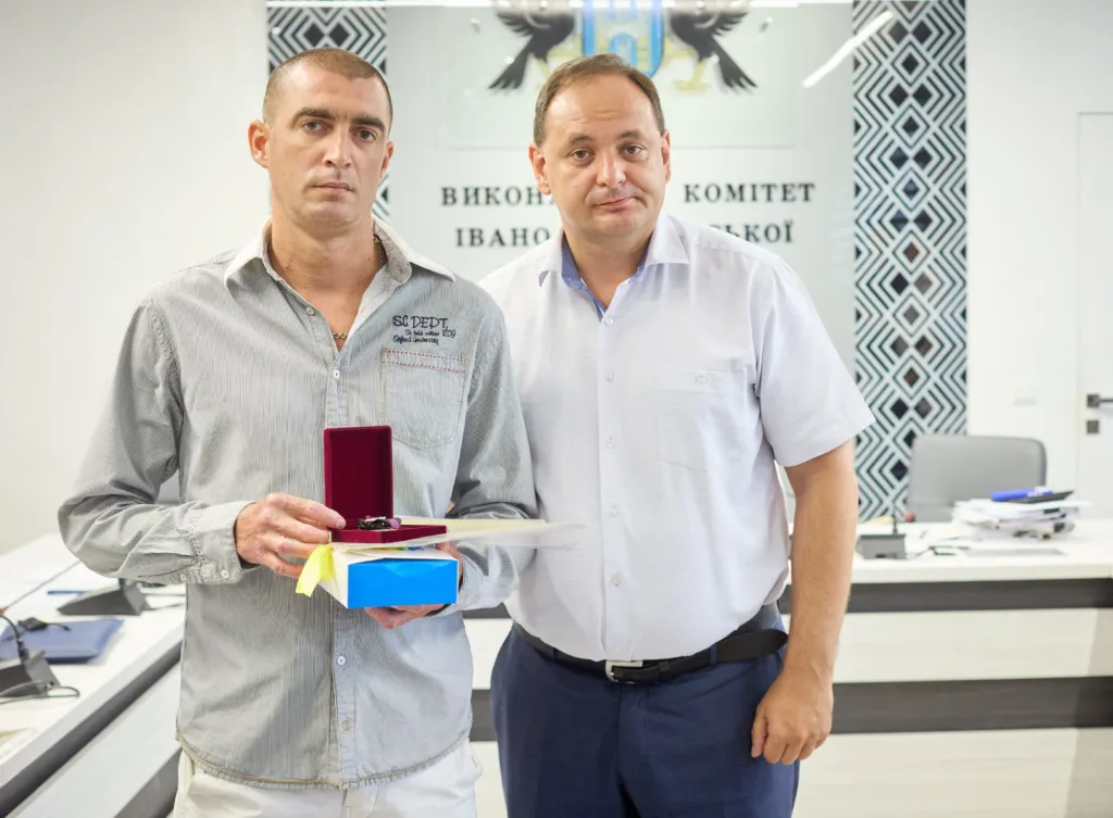 Двоє чоловіків із нагородою в приміщенні виконкому