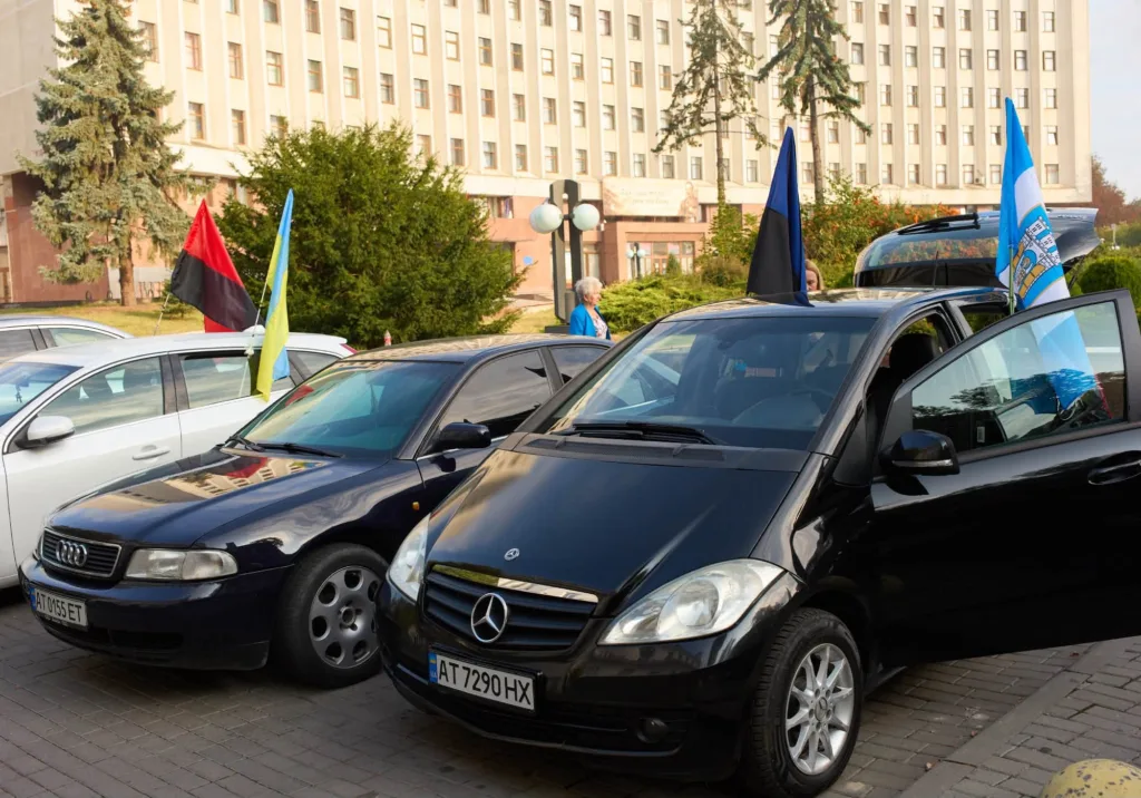 Автомобілі з українськими та міськими прапорами біля адмінбудівлі