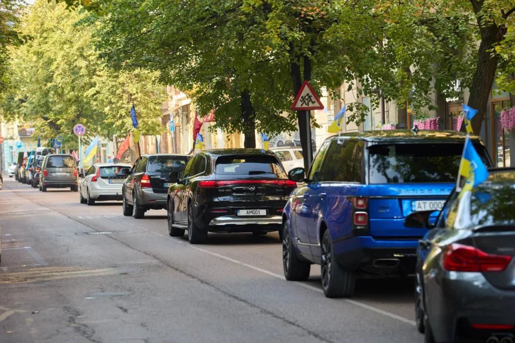 Колона автомобілів з українськими прапорами на міській вулиці