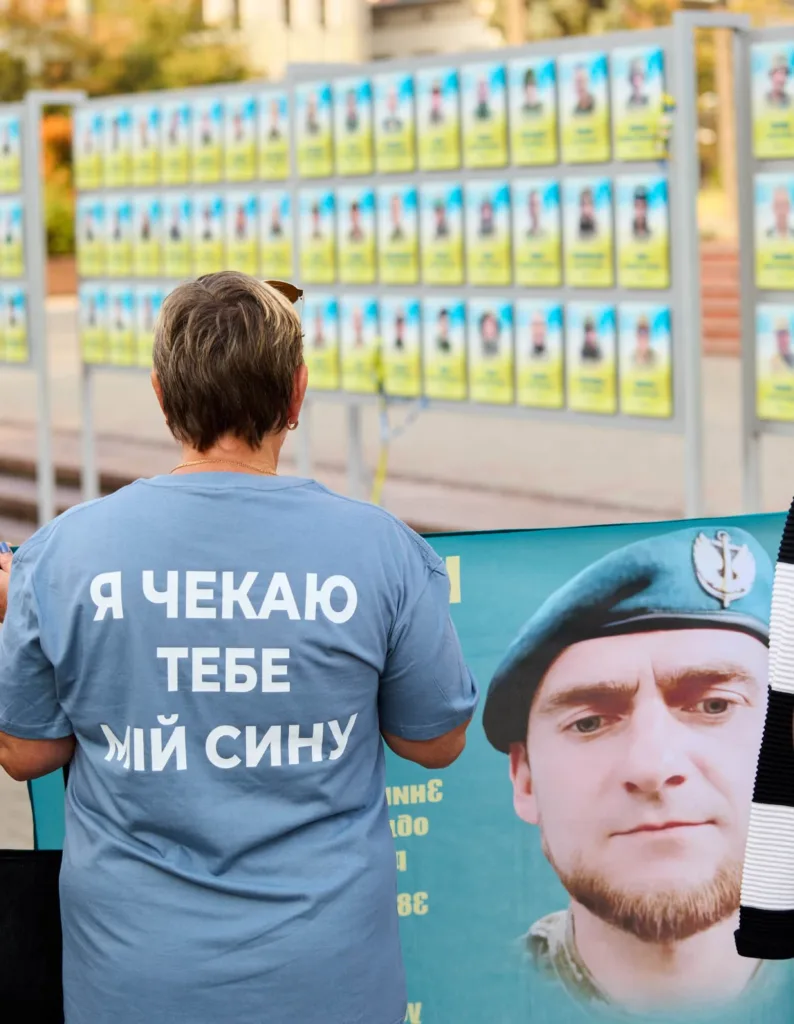 Жінка біля стендів із портретами зниклих військових