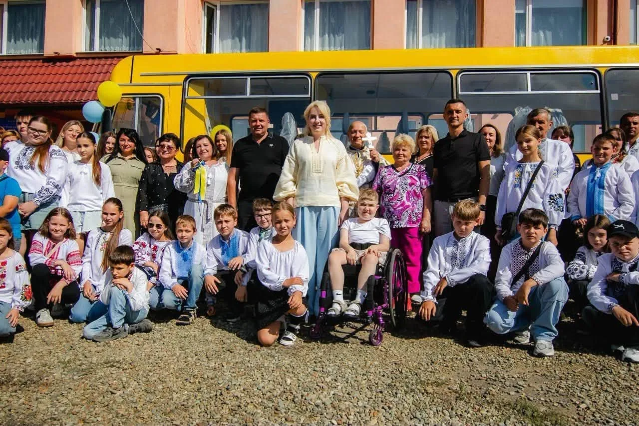 Група дітей і дорослих біля жовтого автобуса