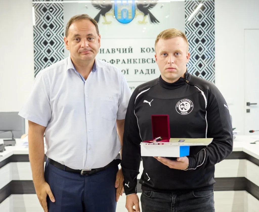 Двоє чоловіків із нагородою в приміщенні міської ради