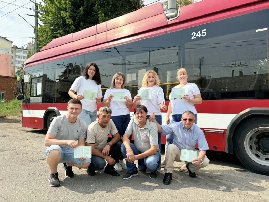 Група людей із документами біля червоного автобуса