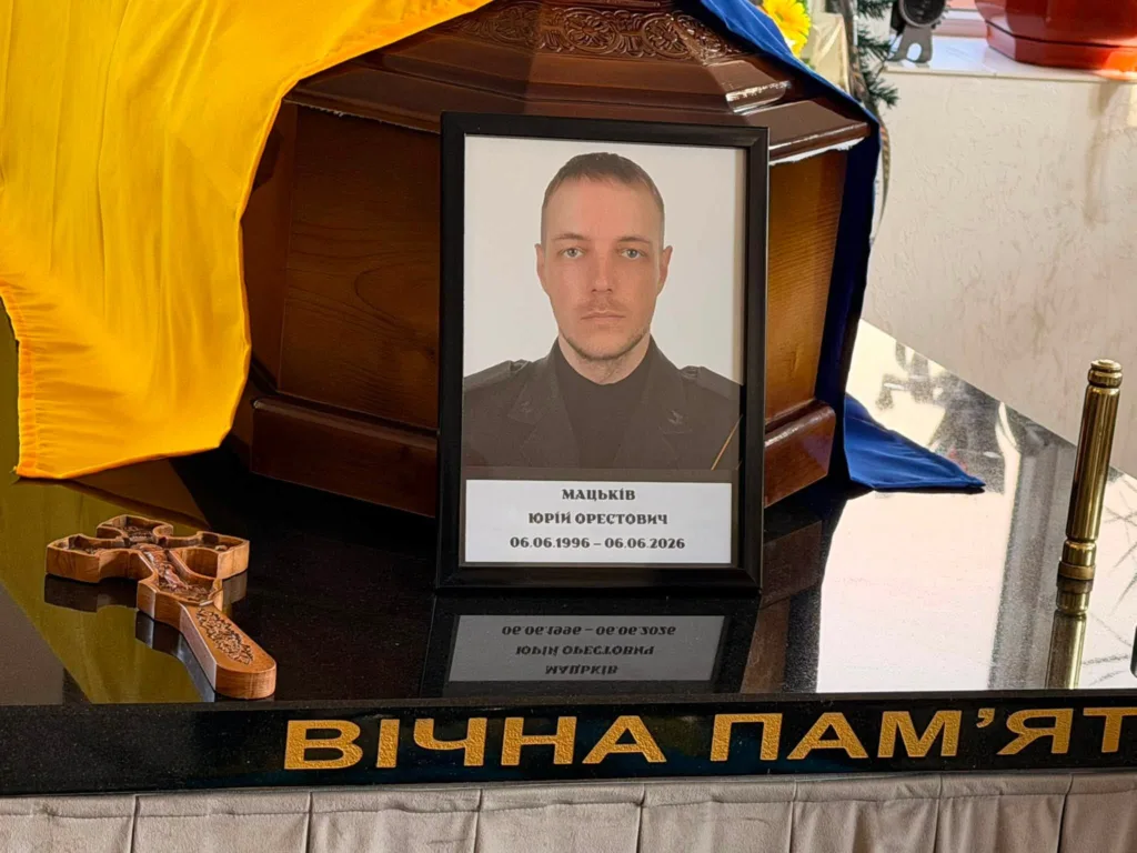 Портрет загиблого захисника біля труни, вкритої прапором України
