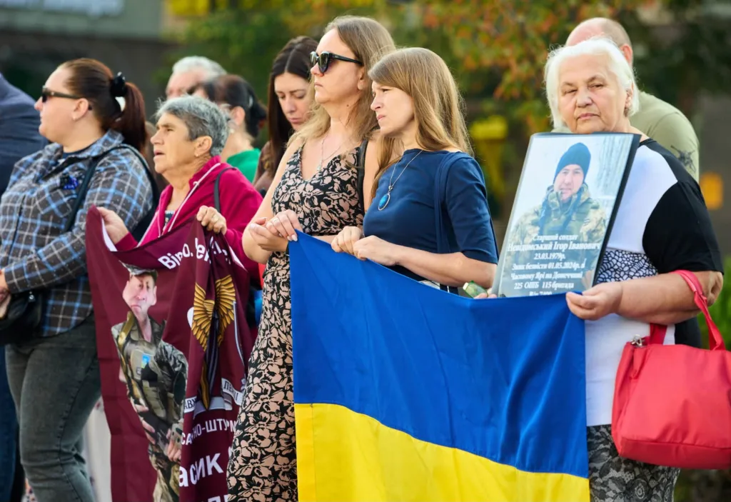 Жінки тримають український прапор і портрет військового