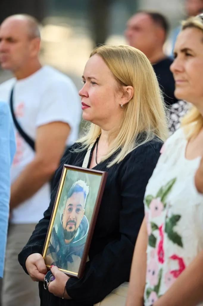 Жінка тримає портрет чоловіка під час жалобної церемонії