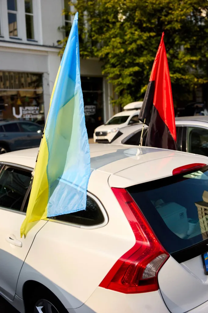 Український і червоно-чорний прапори на білому автомобілі
