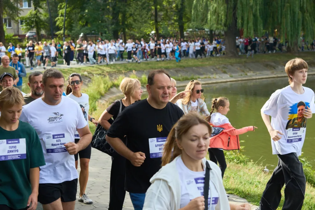 Учасники благодійного забігу біжать вздовж водойми