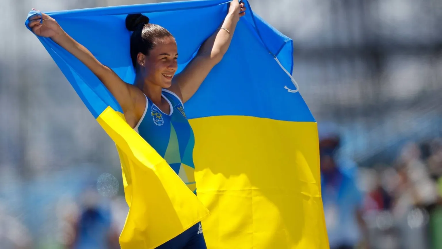 Українська спортсменка тримає державний прапор над головою