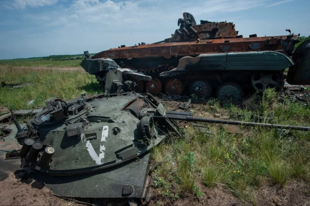 Знищена бронетехніка в полі під блакитним небом