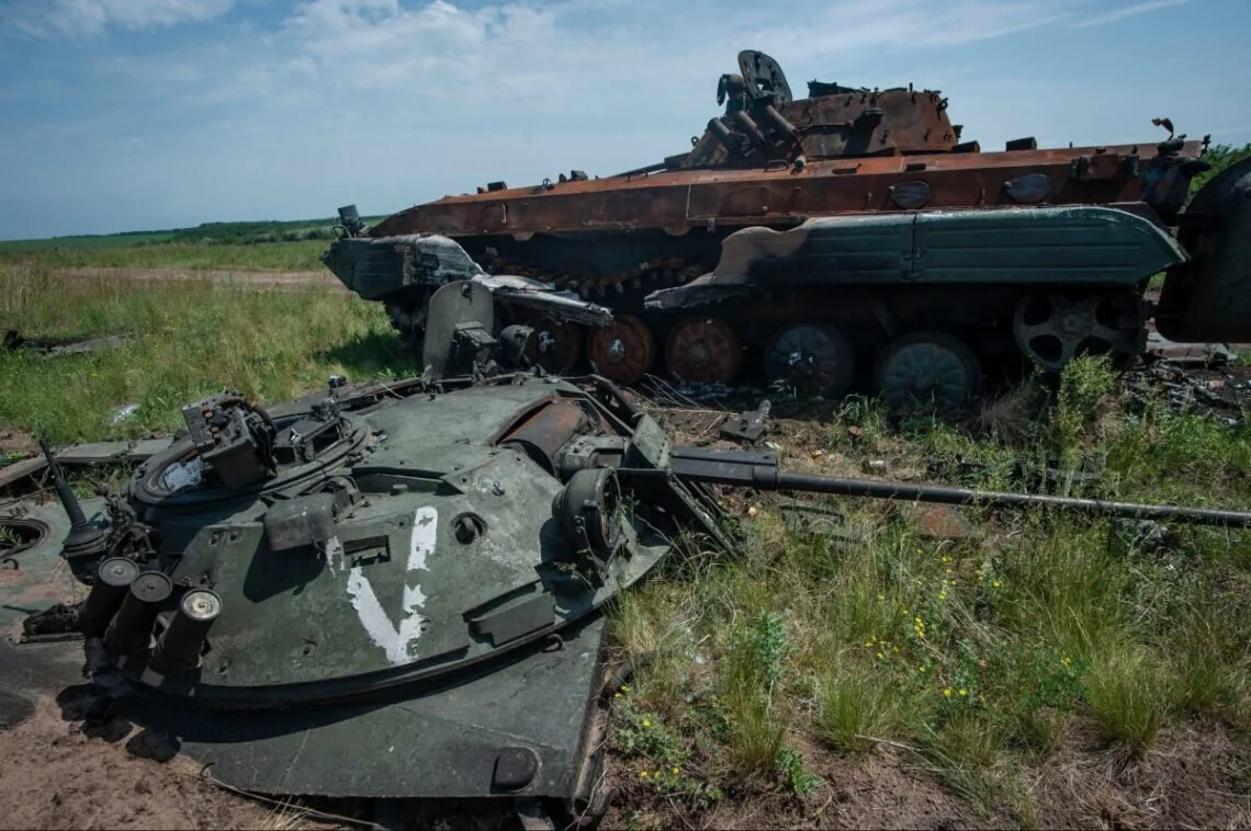 Знищена бронетехніка в полі під блакитним небом