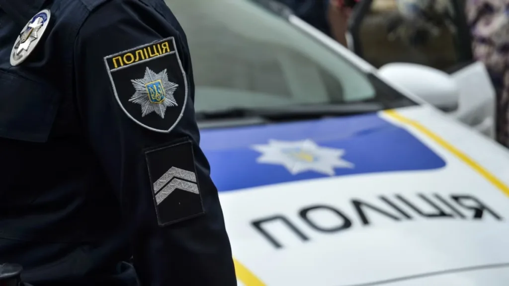 Поліцейський у формі біля патрульного автомобіля