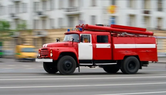Червона пожежна машина мчить міською вулицею