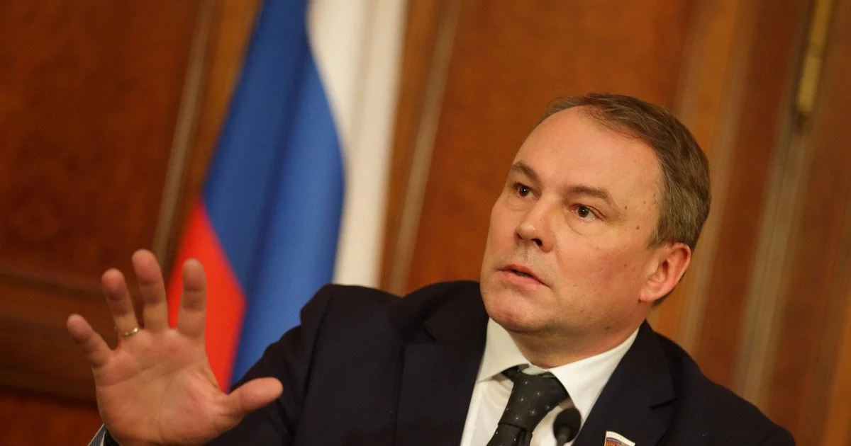 Російський посадовець жестикулює на тлі прапора Росії