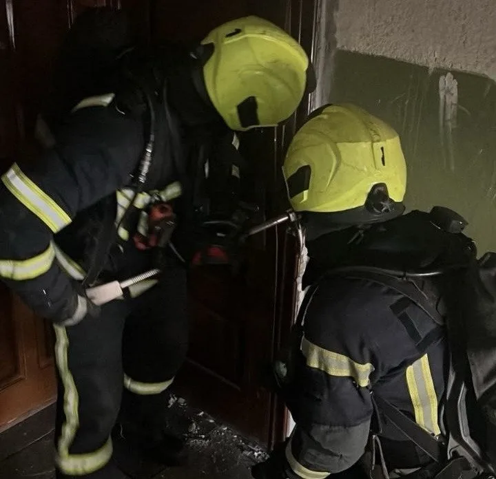 Двоє пожежників у спорядженні біля дверей квартири