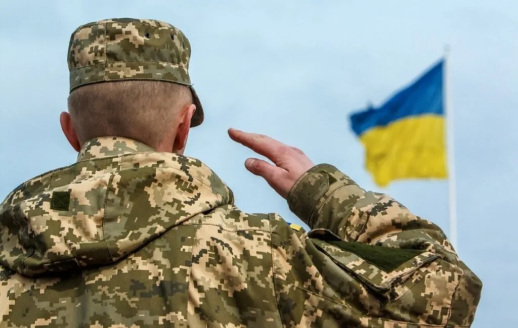 Український військовий віддає честь державному прапору