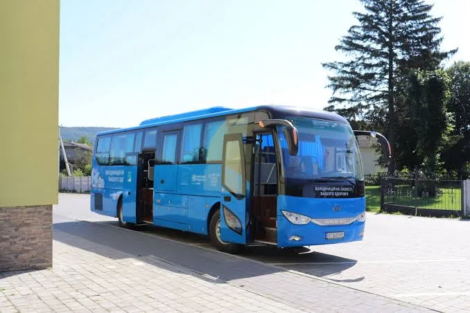 Синій пасажирський автобус біля будівлі