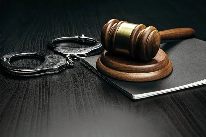 Суддівський молоток і наручники на темному столі