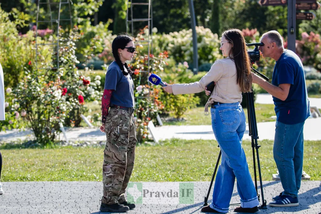 Журналістка бере інтерв’ю в жінки у квітучому парку