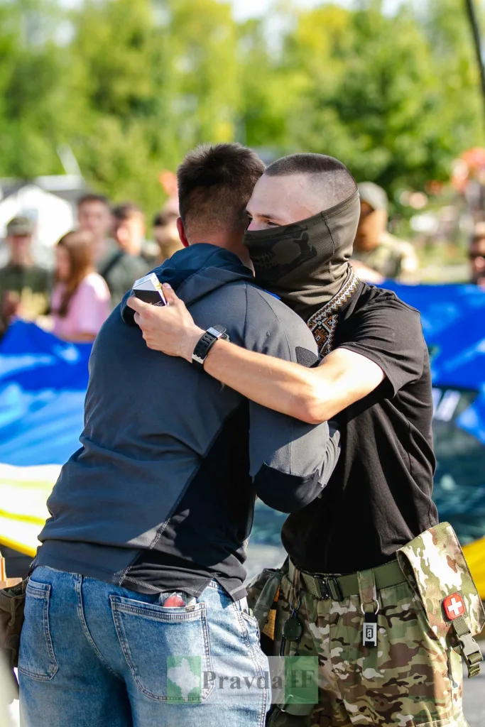 Чоловік у балаклаві обіймає друга на вулиці