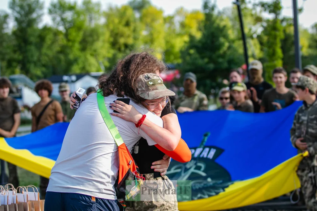Військовослужбовиця обіймає жінку на тлі українського прапора