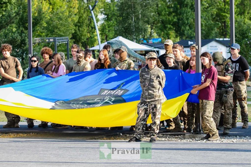 Молодь і військові тримають великий український прапор