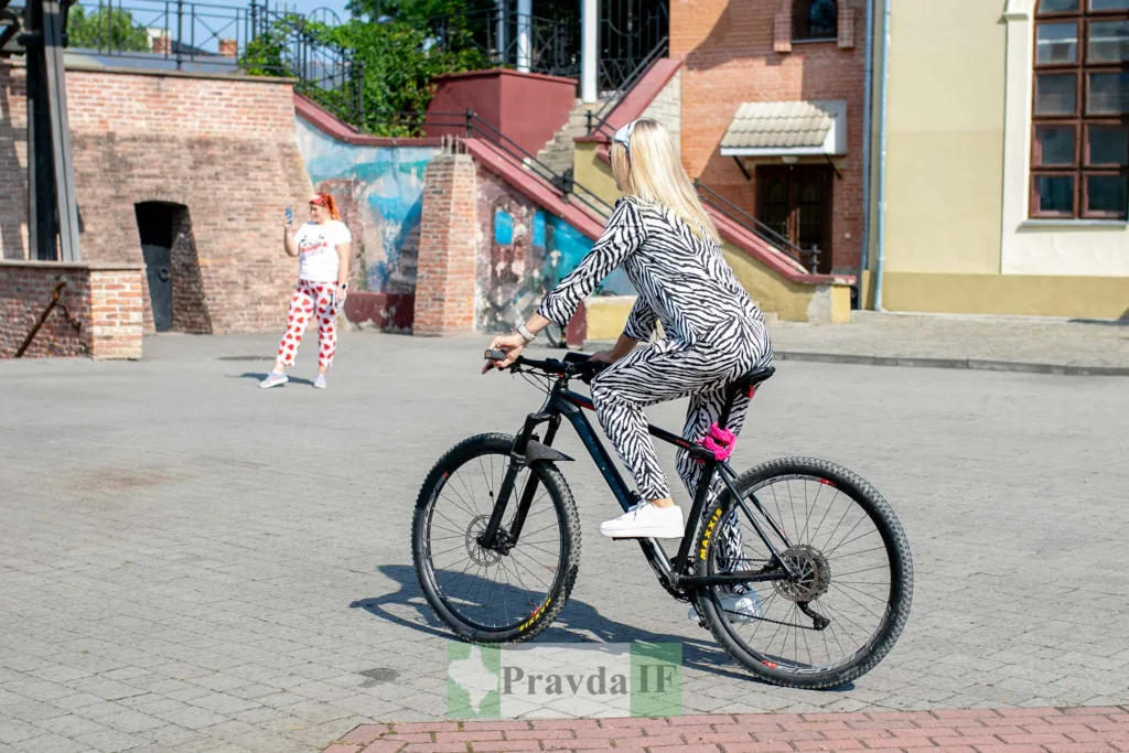 Жінка в зебровому костюмі їде велосипедом містом