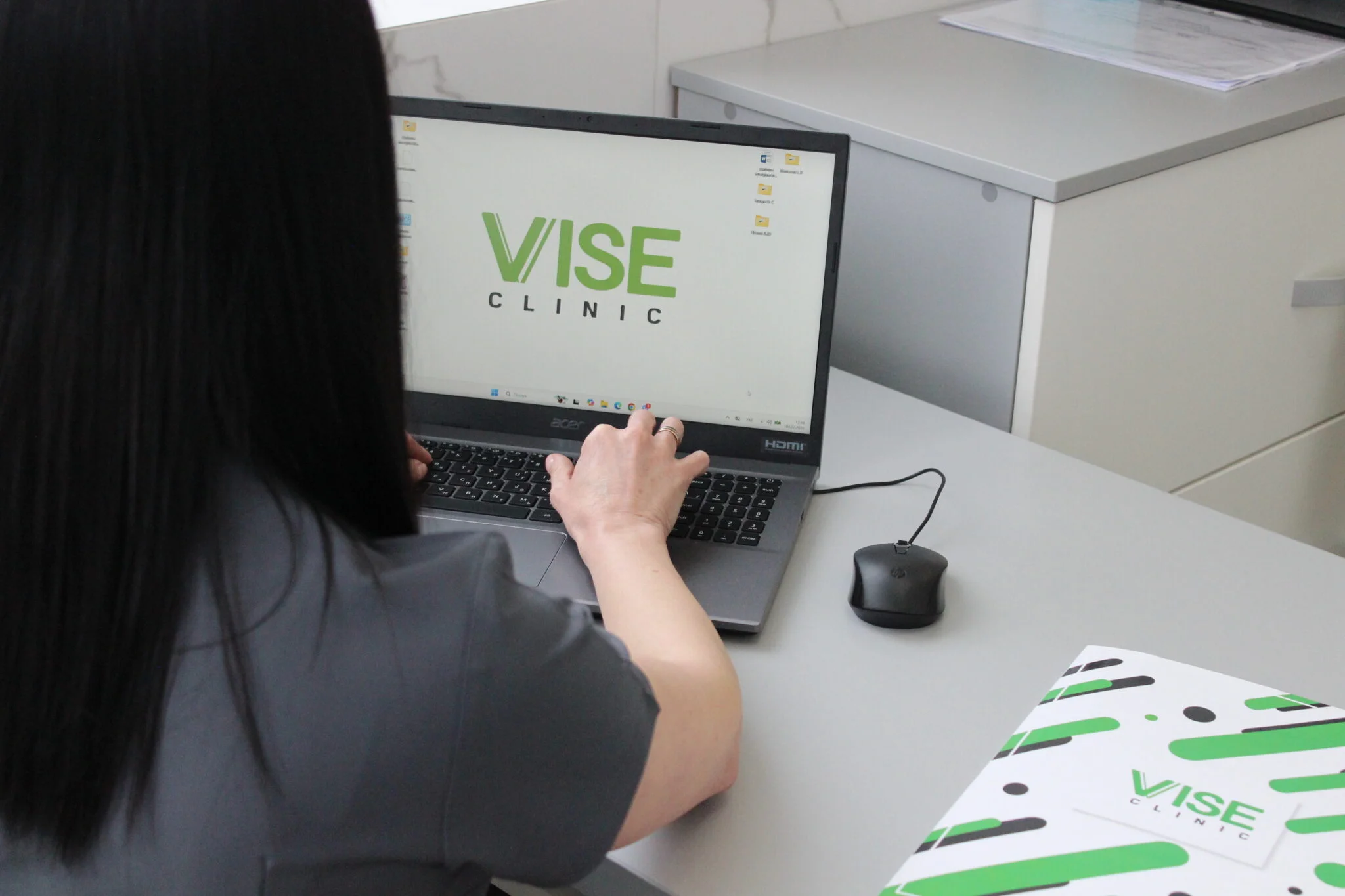Працівниця працює за ноутбуком із логотипом VISE Clinic