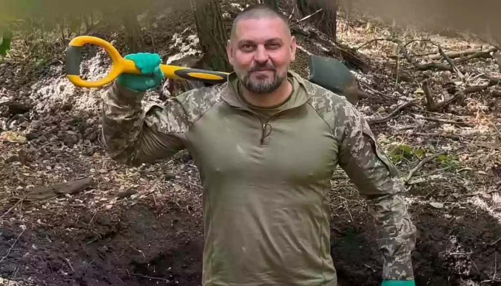 Військовий у лісі тримає лопату на плечі