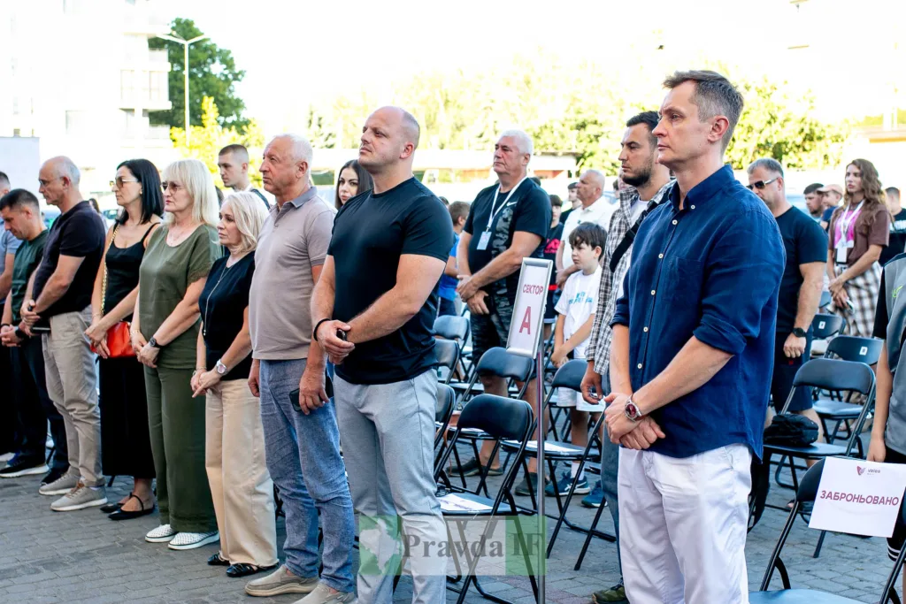 Люди стоять під час урочистого заходу просто неба