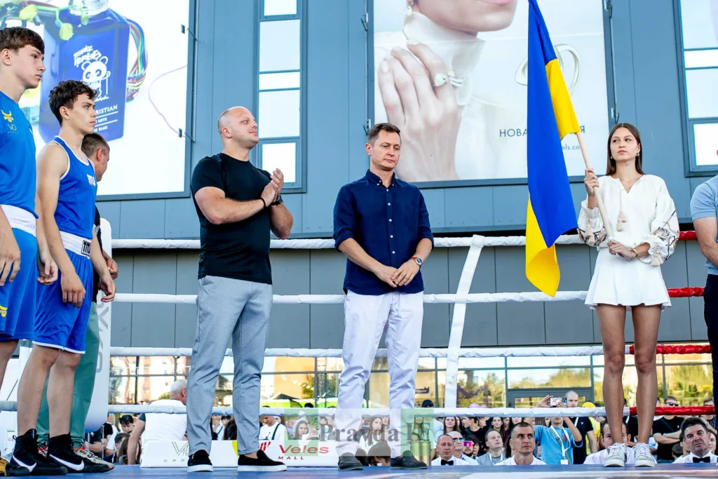 Боксери, організатори та дівчина з українським прапором на рингу