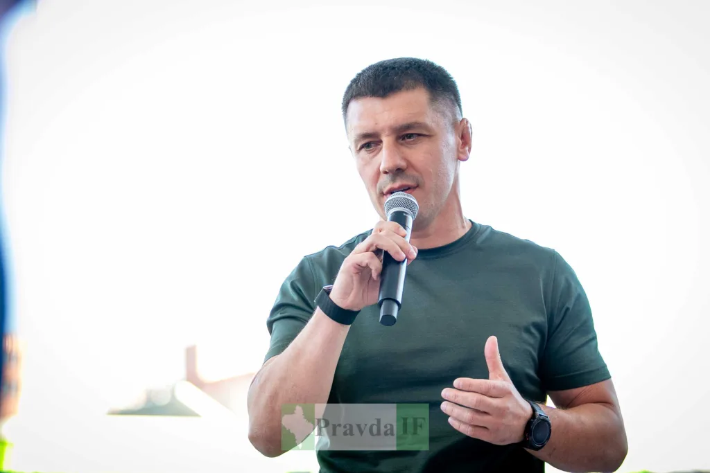 Чоловік у темній футболці виступає з мікрофоном