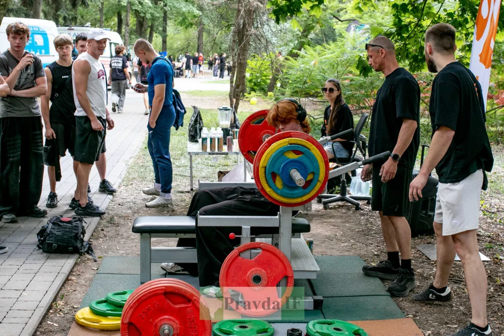 Учасники спортивного заходу біля тренажера з вагами в парку