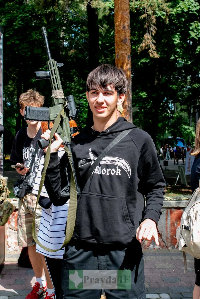 Юнак у лісі тримає зелений автомат