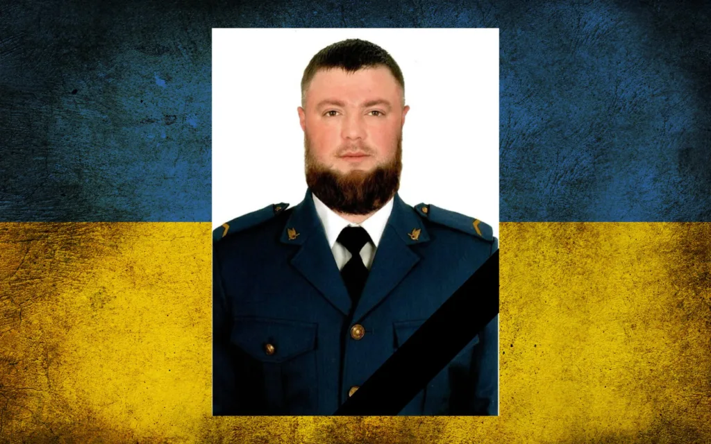 Портрет військовослужбовця з траурною стрічкою на тлі прапора