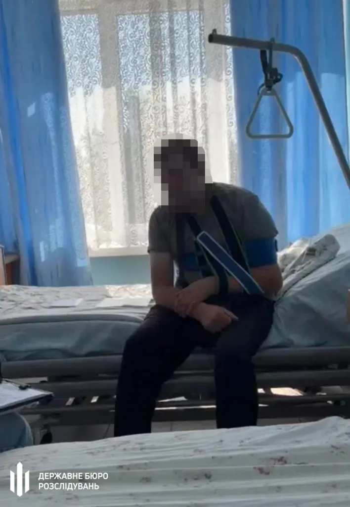 Чоловік із травмованою рукою сидить на лікарняному ліжку