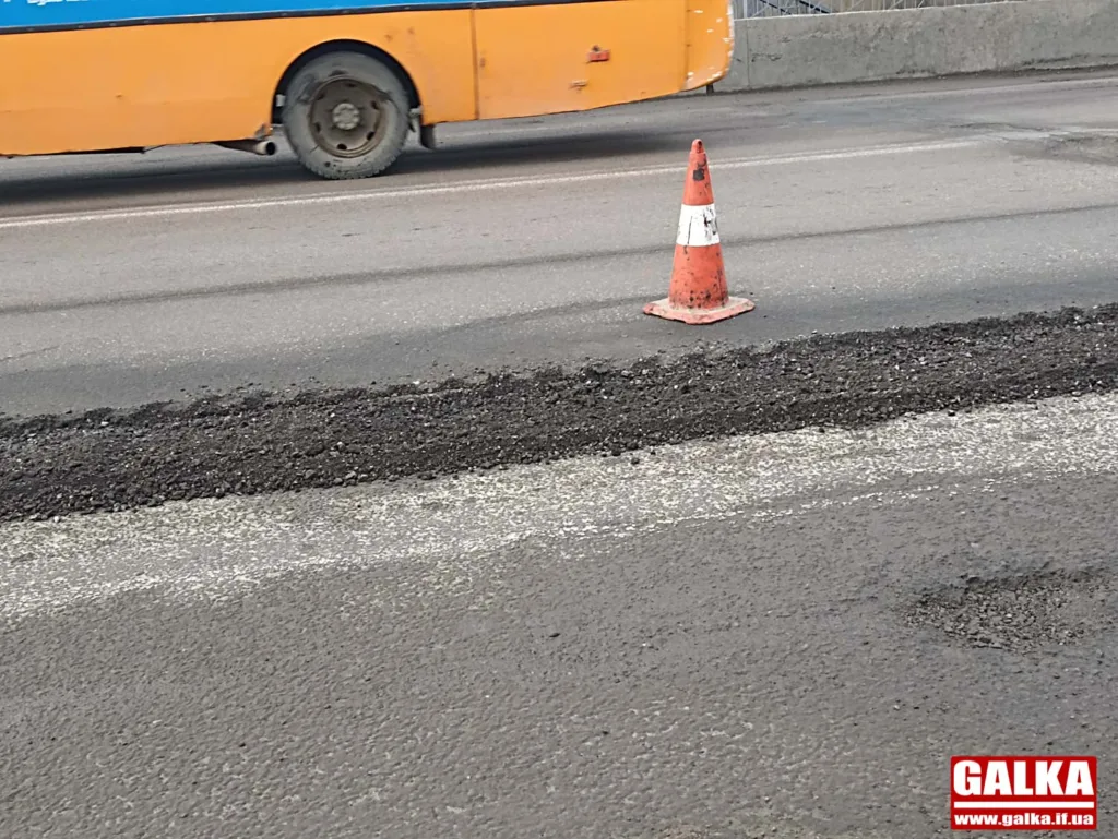 Дорожній конус біля свіжого асфальту та автобуса