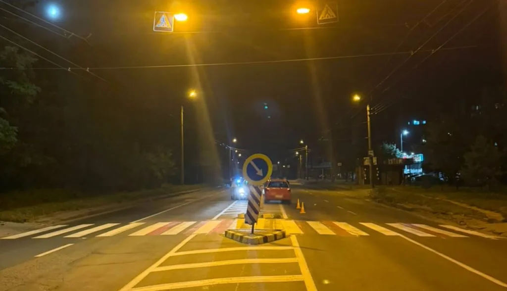 Нічний пішохідний перехід із дорожнім знаком та автомобілями