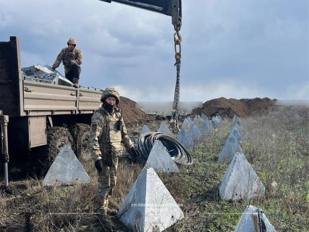 Військові встановлюють бетонні протитанкові піраміди в полі