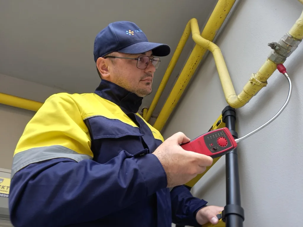 Газовик перевіряє витік газу на жовтій трубі