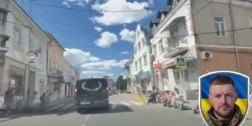 Міська вулиця з автобусом і портретом військового на тлі прапора